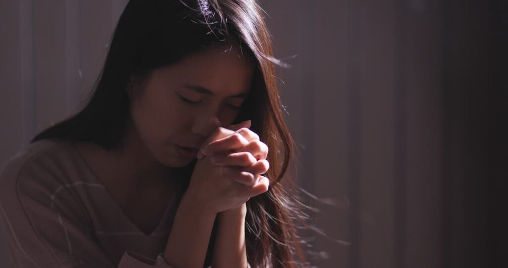 Christian woman kneeling down in daily prayer.