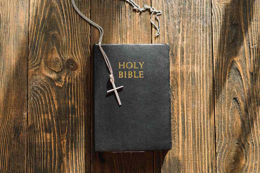A chain with a cross lies on top of a Bible.